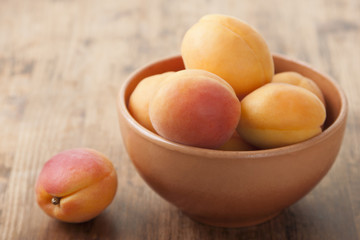 Apricots in a clay bowl on a wooden table