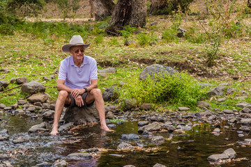 Elderly Australian man sitting by a creek.