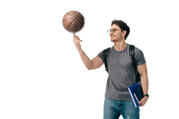 Fototapeta premium happy handsome student spinning basketball ball on finger isolated on white
