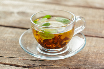 cup of black tea with mint leaves on a wooden table