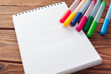 Office desk table top view. Notepad with blank pages on wooden table