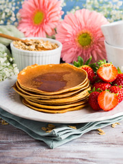 Stack of oatmeal flour pancakes with strawberries on white dish