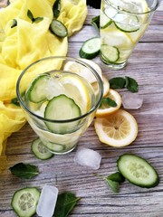 detox water in glass, sliced lemon and cucumber with ice to cleanse the body