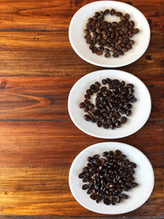 Kinds of coffee beans,  Different of coffee beans roasts.coffee beans in the white dish on the wooden table.