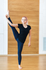 Yogi woman with pink hair practicing yoga, standing in Utthita Hasta Padangustasana exercise,...