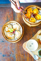 Prawn gluten free dumplings. Chicken curry steamed dumpling.  A hand with chopsticks holds a piece. Wooden table background in a restaurant. Traditional Chinese cuisine. Top view with copy space