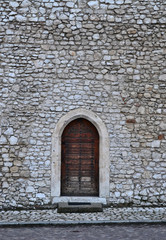 Old, traditonal brown door in white castle wall