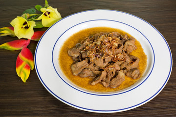 Stir pork slice with coconut sugar sprinkle with fried shallot slice (Sweet pork) in white dish Thai food, Decorated dish with flower for beautiful..