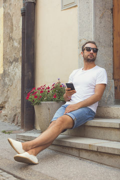 Modern guy using cellphone in the European city.