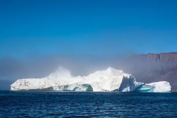 Iceberg making the fog. Frozen air near mountain of ice.
