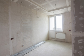 Interior of the renovated room in a new building, plastered walls, mounted ceiling and cabinet