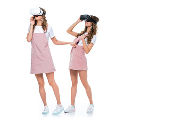 surprised twins watching something in virtual reality headsets isolated on white