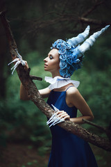 Beautiful model is posing in a forest with blue horns 