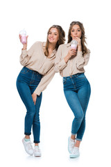smiling attractive young twins drinking milkshakes isolated on white