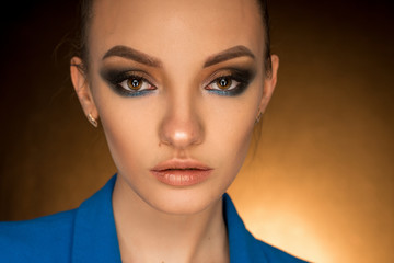 Beautiful young girl in blue jacket with beauty makeup in studio