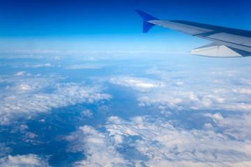 Fototapeta na wymiar Airplane Wing in the Blue sky. View from a plane window