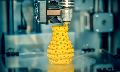 3d printer printing objects yellow form closeup. Modern technical 3D printing.