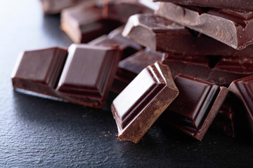 Broken chocolate pieces on black background.
