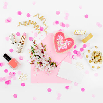 Pink envelope with a spring flower arrangement and accessories. Flat lay, top view.