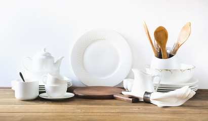Fototapeta na wymiar White kitchen utensils, dishware and other different white stuff for serving on white wooden board.