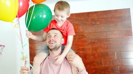 Little boy on the daddy's kneck with colored ballons