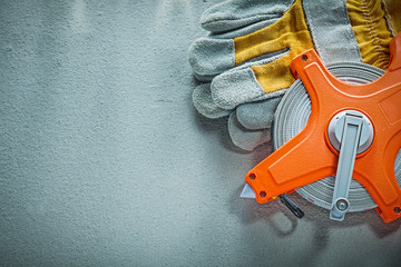 Safety gloves tape measure on concrete background