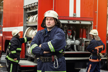 Fireman (firefighters) in action standing  near a firetruck. Emergency safety. Protection, rescue from danger.