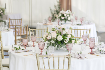 Beautiful table setting with crockery and flowers for a party, wedding reception or other festive event. Glassware and cutlery for catered event dinner. - obrazy, fototapety, plakaty