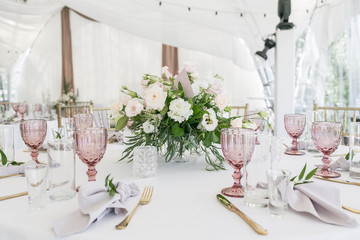 Beautiful table setting with crockery and flowers for a party, wedding reception or other festive event. Glassware and cutlery for catered event dinner.