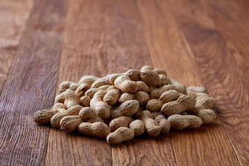 Unpeeled peanuts on a wooden background, top view, selective focus, shallow depth of field.
