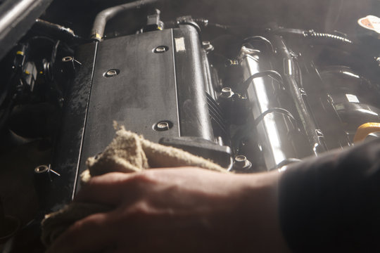 Wipe cleaning the car engine with green microfiber cloth