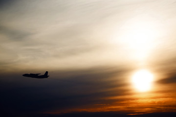 plane flying at sun in sunset sky. airplane in the air. transportation concept with space for text.  Silhouette of a big passenger or cargo aircraft in sun light and clouds.