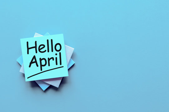 Hello April greeting written on blue paper stack at desk with empty space for text, mockup or template
