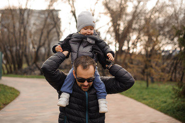 Father in eyeglasses carrying little son on his shoulders