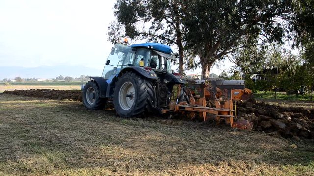 Tractor digging furrows in the ground