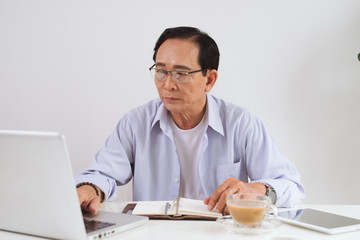 Senior man working with laptop and basic things for work at his desk