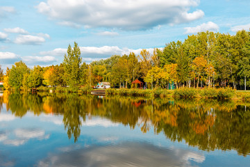 Obraz premium Beautiful lake with mirror reflections in clear water on sunny day. Tranquil landscape with lake, cloudy sky, and trees reflected symmetrically in the water. Salt lake (Sosto) Nyiregyhaza, Hungary