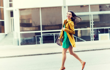 fashion and people concept - happy young woman or teenage girl running on city street