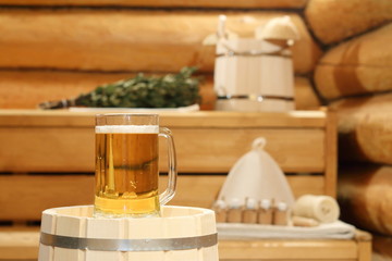 A mug of  light beer on a barrel in the sauna on the background of bath accessories.