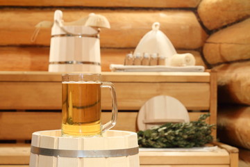 Fototapeta na wymiar A mug of light beer on a barrel in the sauna on the background of bath accessories.