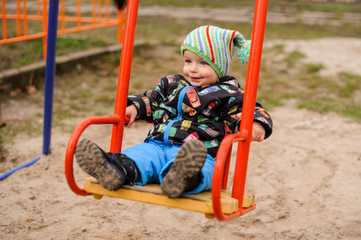 Sweet toddler boy smiling on a swing