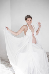 photo Pregnant woman holding a white drapery in the hands like wings