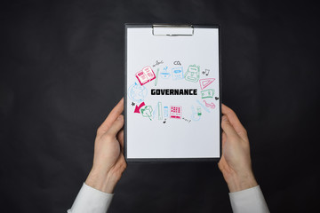 In the hands of a businessman a notebook with the inscription:GOVERNANCE