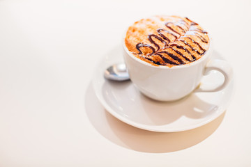 A cup of cappuccino on a saucer with spoon