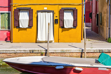 Fototapeta na wymiar Daylight view to boat parked in local canal near sidewalk