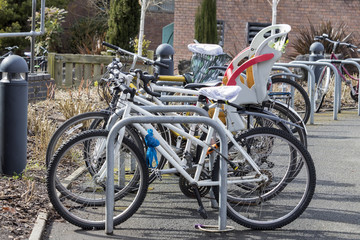 Bicycles chained in a rack with one including a child seat