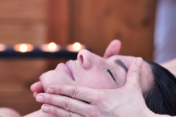 A beautiful young girl (woman) having a massage in the spa salon, a romantic setting, a pink flower behind the ear. Concept: spa procedures, body massages, spa creams, relax, spa water treatments.