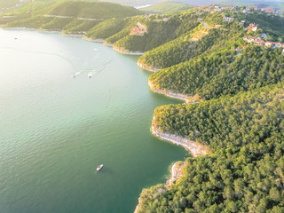 Fototapeta premium Aerial trees and cliff rock wall, bluffs at Lake Travis, Austin, Texas, USA. Luxury vacation homes and house on coastline. Looking down houses in community, ocean crystal background