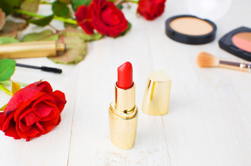 Obraz na płótnie Canvas Various cosmetic products for make-up with red roses on a white wooden background with copy space. Makeup Accessories Red lipstick Selective focus.