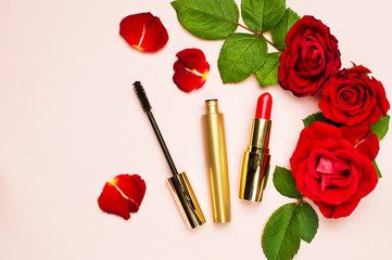 Obraz na płótnie Canvas Various makeup products Red Lipstick Mascara with red roses on a pink background with copy space top view Flat Lay